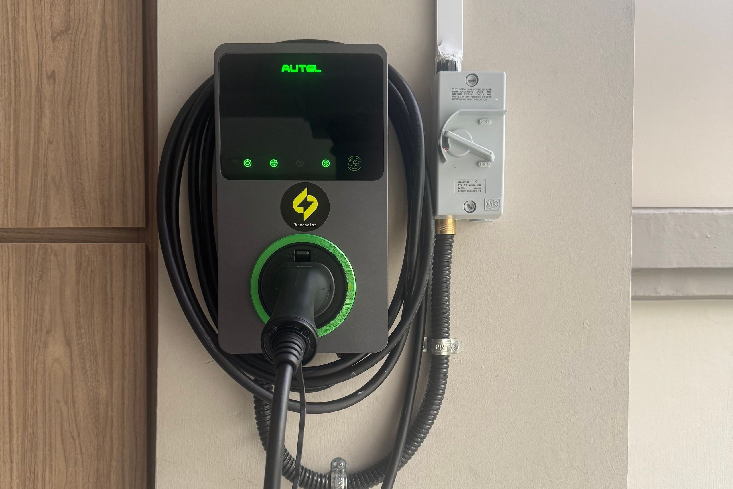 Autel wall charger installed beside a timber door, the plug docked and its cable coiled behind