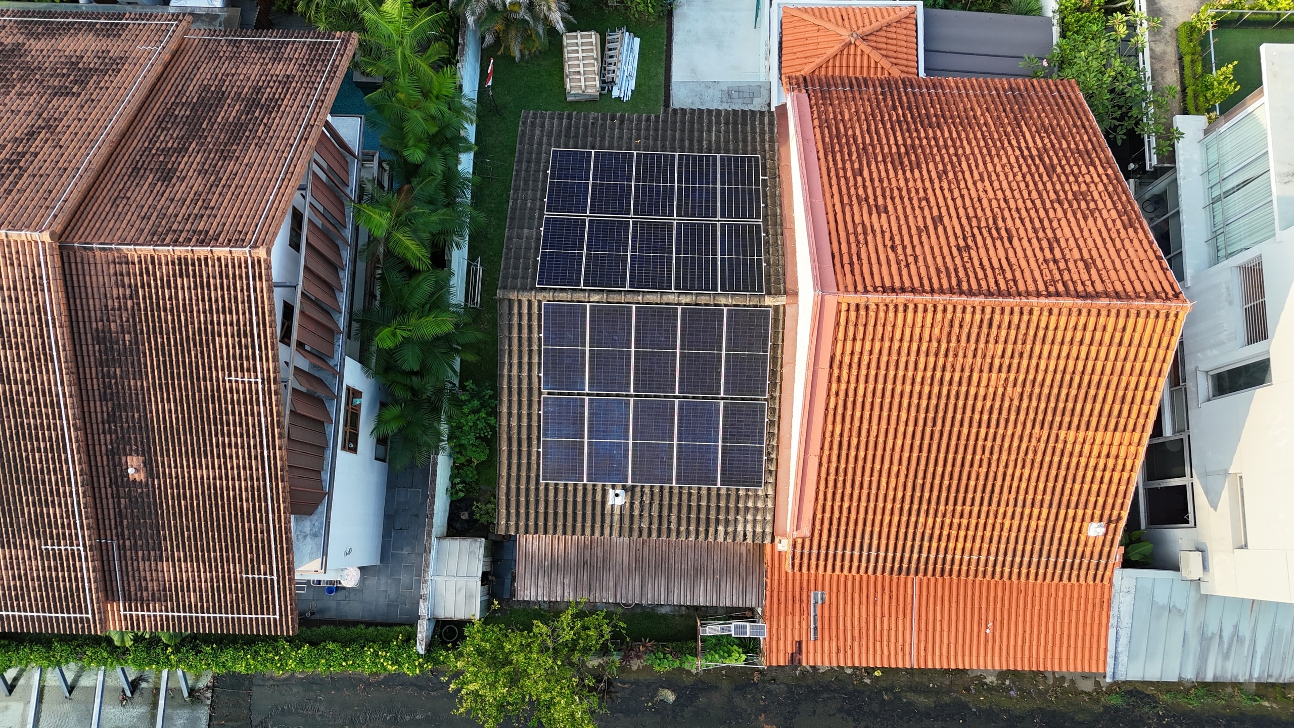 Drone view of a semi-detached house in Bukit Timah with solar panels on its terracotta roof, neighbours either side