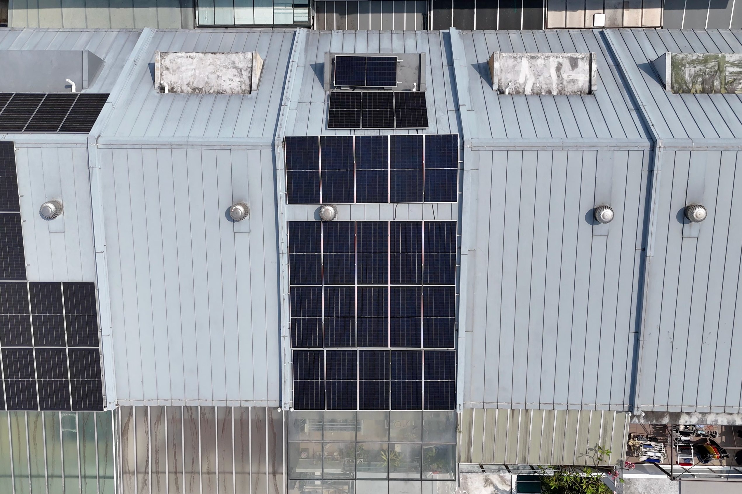 Drone view straight down onto a row of terrace houses in Sembawang, rows of solar panels on the middle metal sheet roof and more next door