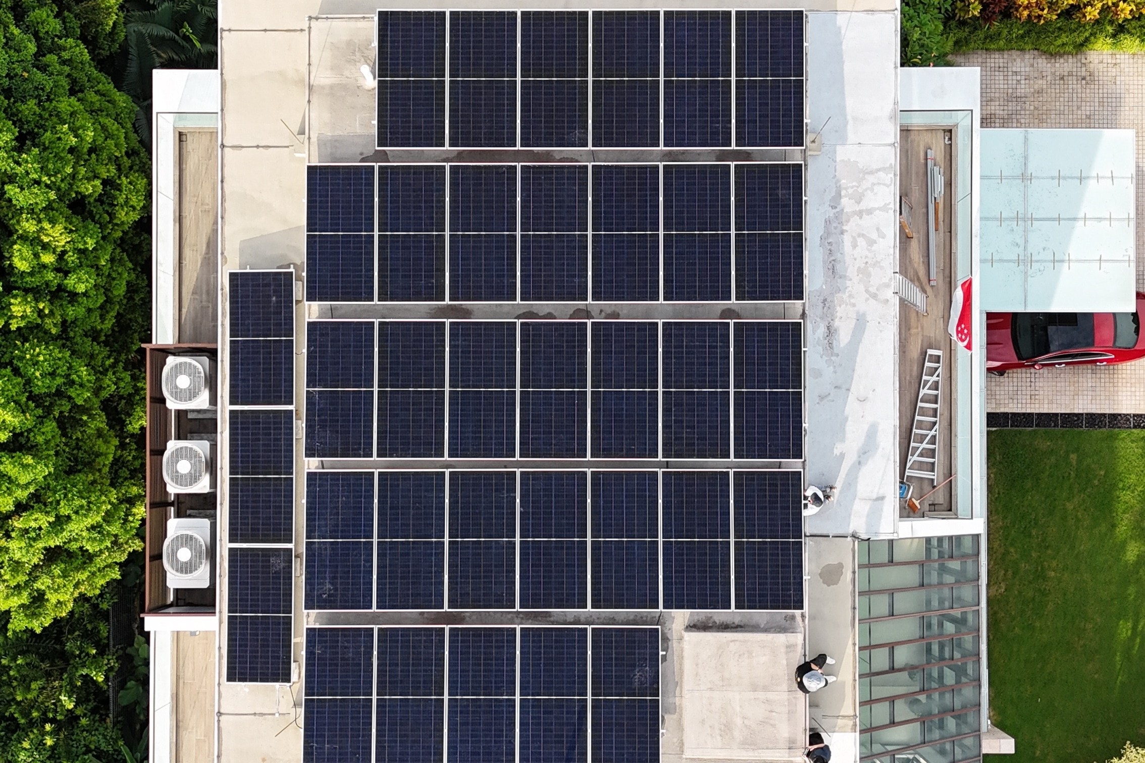 Drone view straight down onto the Stevens Road house, five rows of panels across its flat roof and a narrow row along one side